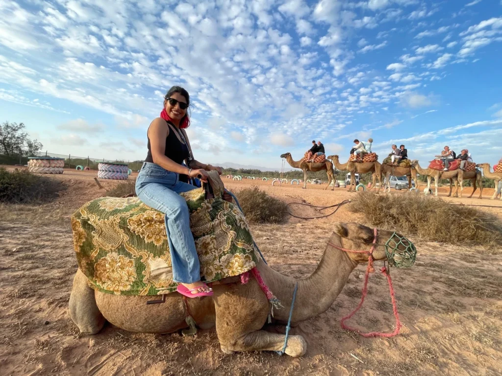 Visitor sitting on a camel with a line of camels walking behind under a blue sky